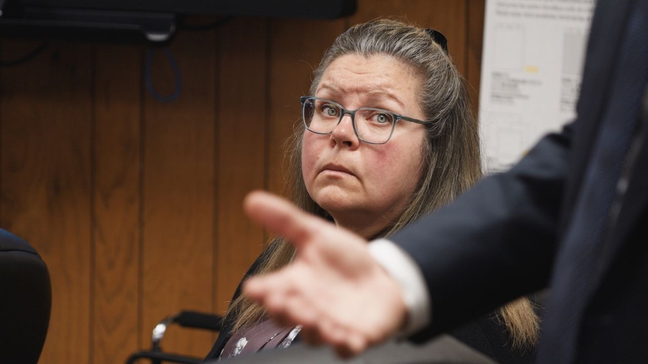 a woman with glasses looking up at a person